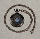 BKB Custom Gifts blue ornate pocket watch with intricate metal filigree cover and matching chain on wooden surface