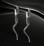 BKB Custom Gifts serpent hoop earrings with black stones and green eye accents on a dark abstract background.